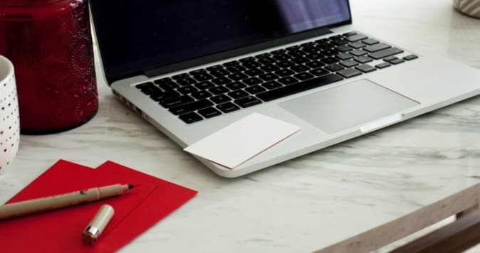 Open laptop with pen and writing pad sitting beside it