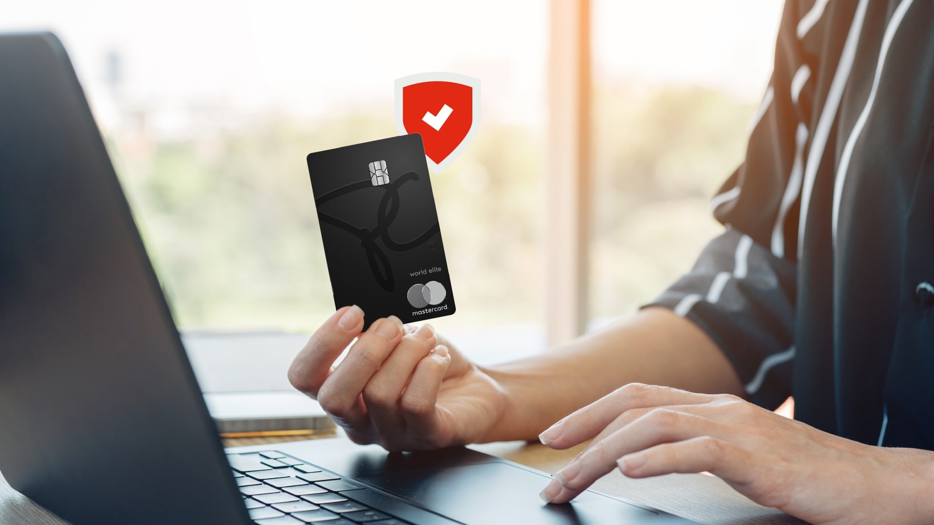 Client utilisant un ordinateur portable avec une carte Mastercard PC en main.